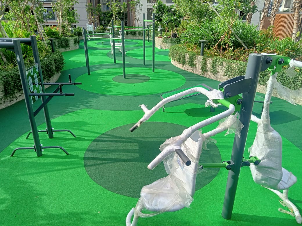 Green EPDM wet pour surfacing around outdoor fitness equipment