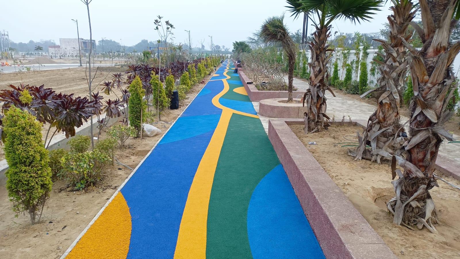 Blue and yellow EPDM wet pour jogging and walking track through a park