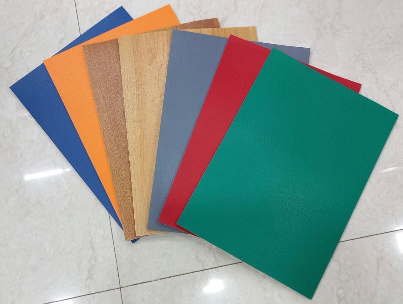 Fan of PVC vinyl sports flooring samples in blue, orange, maplewood, oakwood, grey, red and green