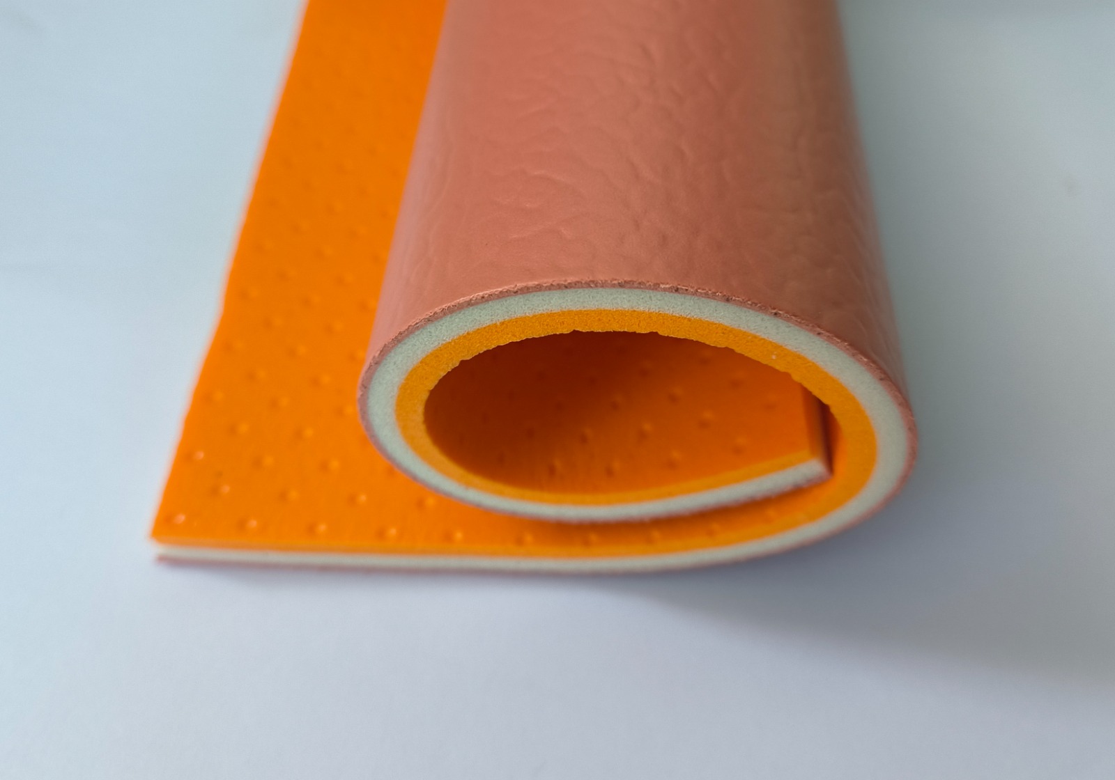8 mm PVC vinyl roll cross-section showing orange wear layer over the foam backing