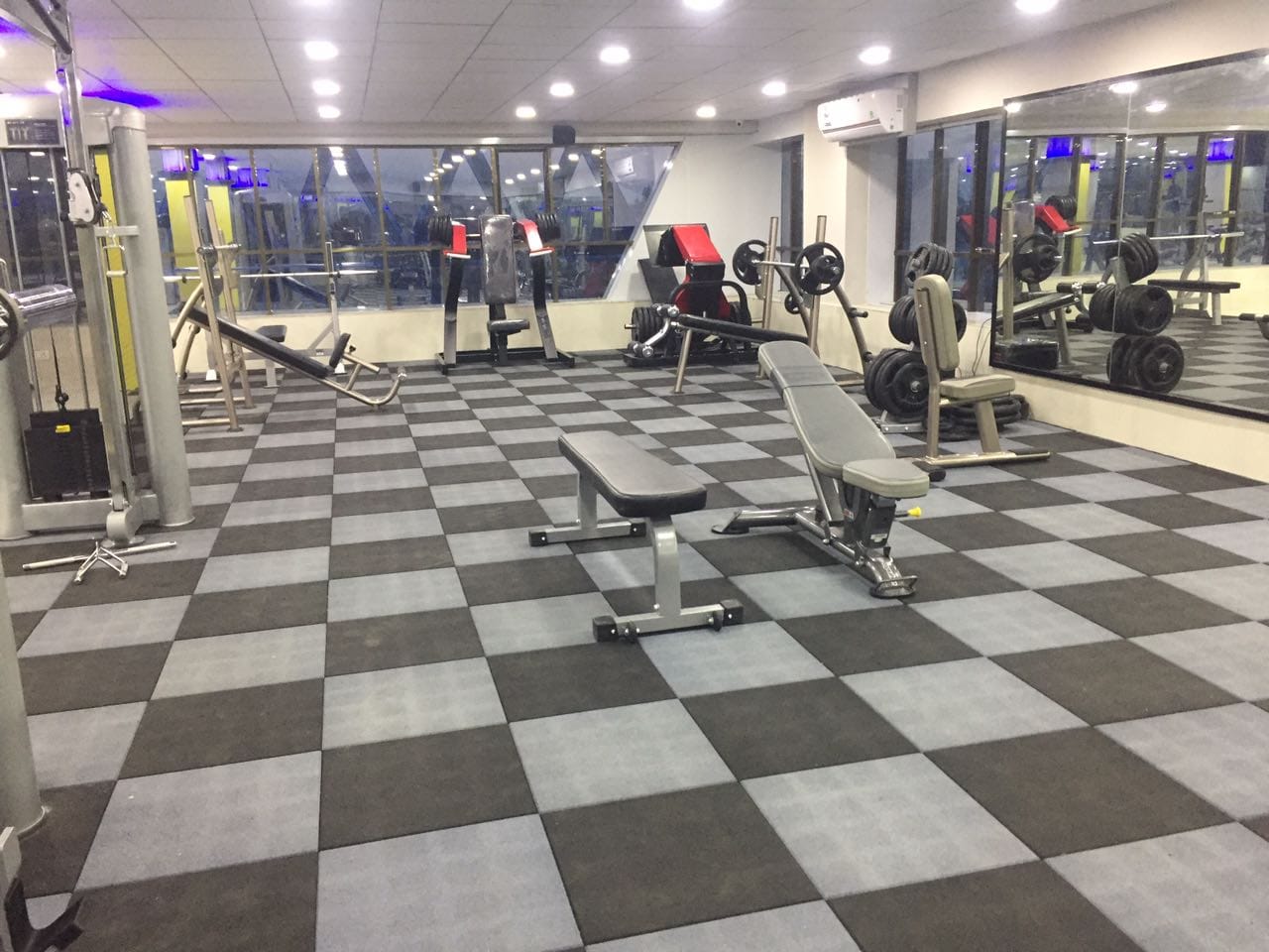 Square rubber gym tiles in black and silver grey under strength training equipment